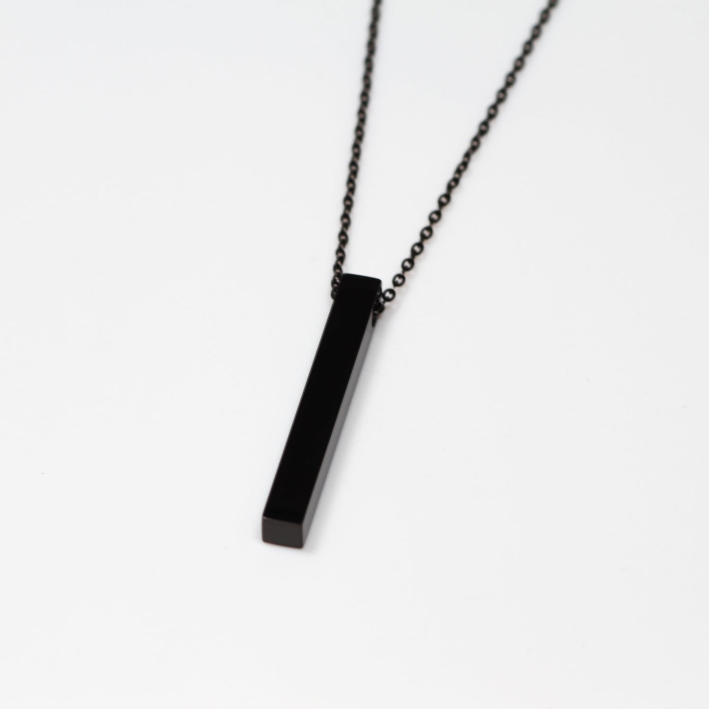 Black rectangular pendant on a chain against a white background