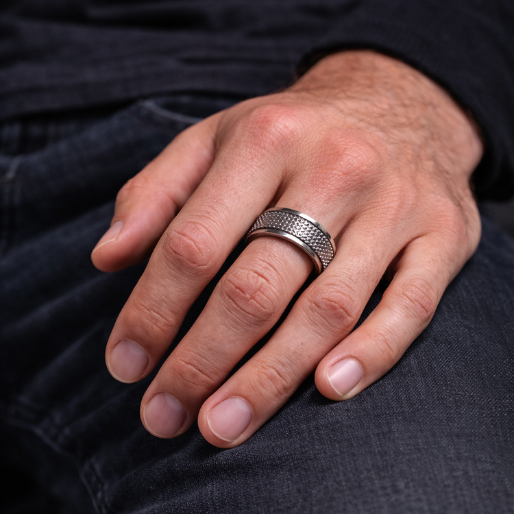 Hand wearing a silver ring on a dark background