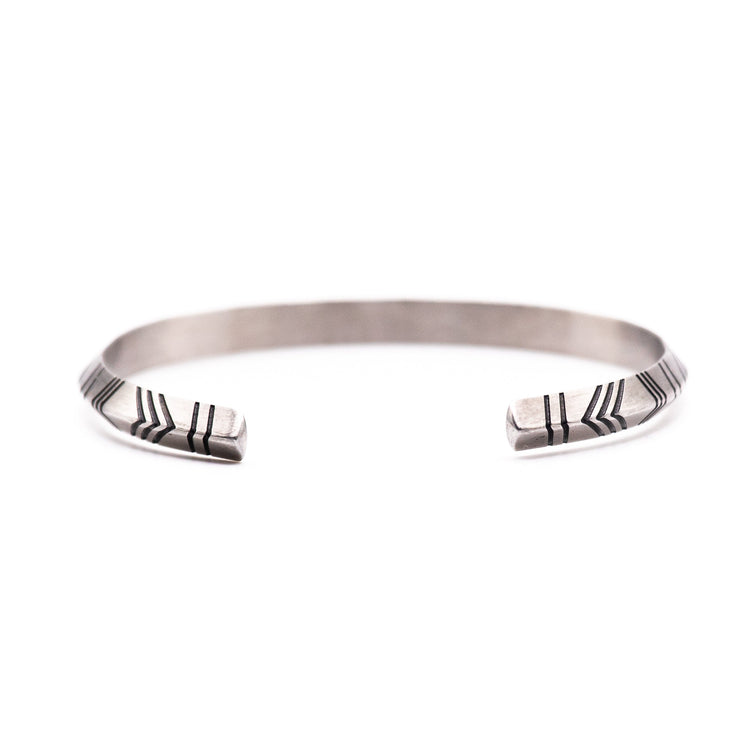 Silver bracelet with arrow pattern on a white background