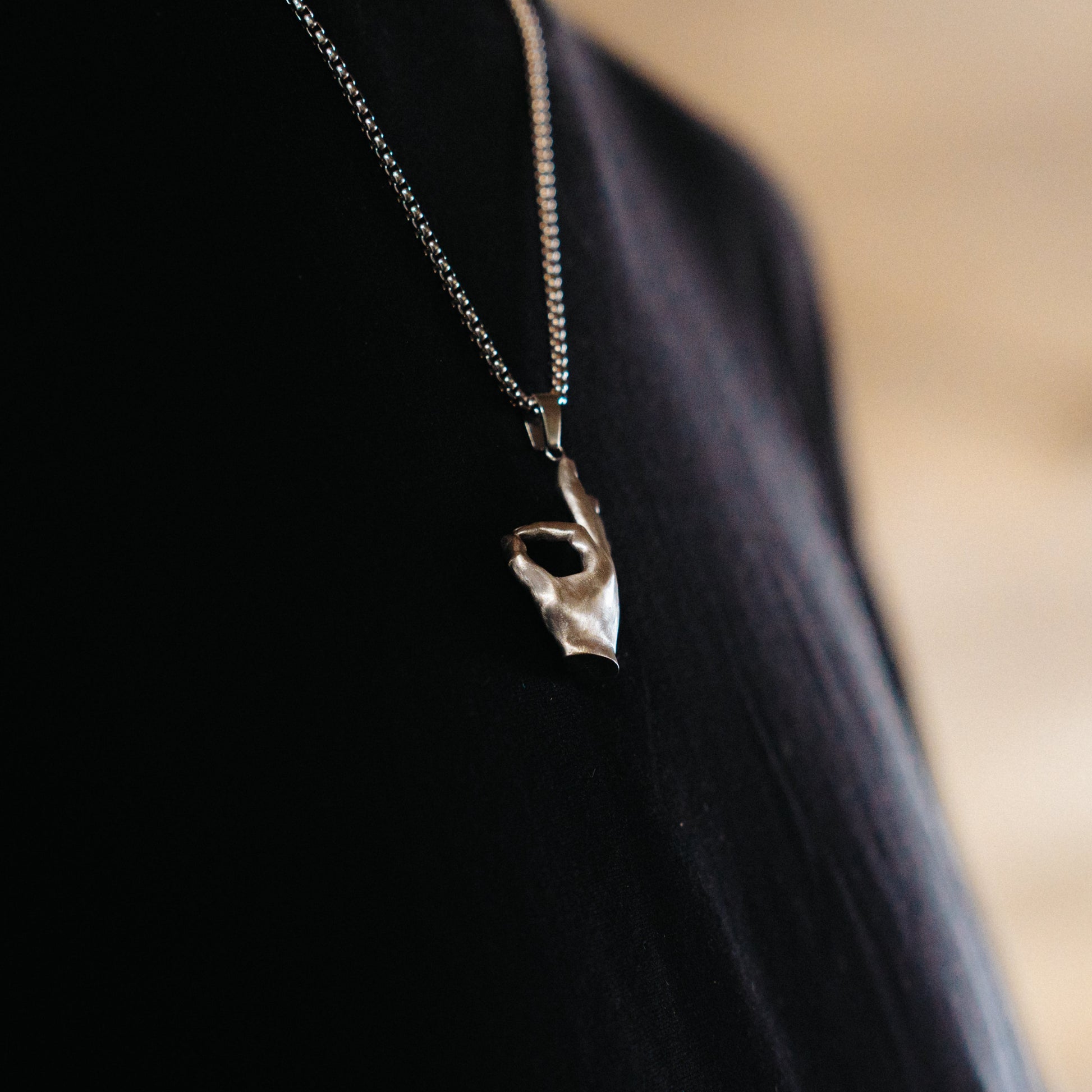 Necklace with a Stainless Steel Pendant pendant worn by a person against a blurred background