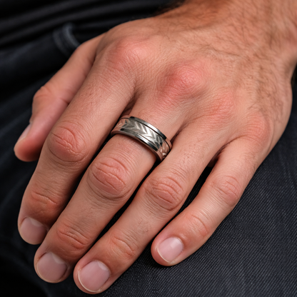 Hand wearing a silver ring on a dark background