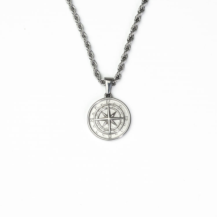 Close-up of a silver stainless steel compass pendant with sleek detailing and water-resistant finish.