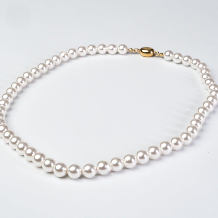Pearl necklace with a gold clasp on a light gray background