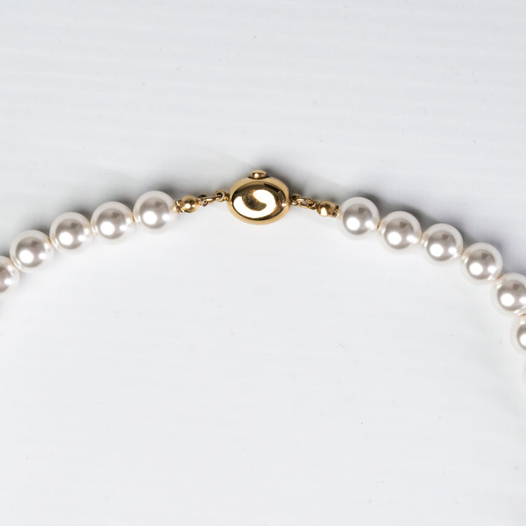 Pearl necklace with a gold clasp on a light gray background