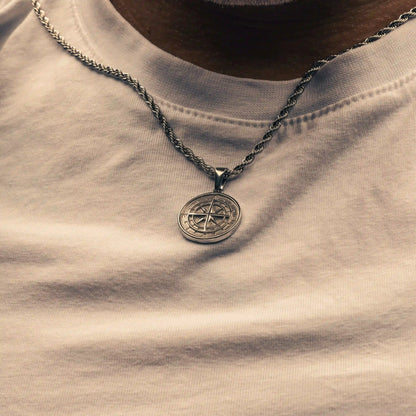 Necklace with a compass pendant on a light-colored shirt