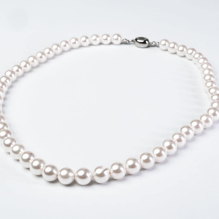 Pearl necklace with a silver clasp on a light gray background